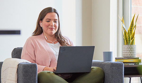 Smiling woman wearing headphones with computer on lap