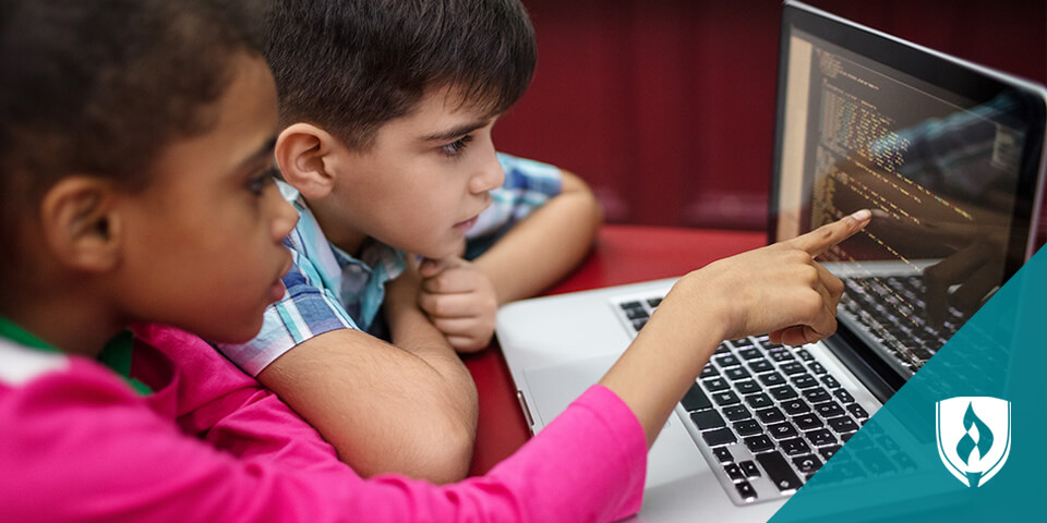 boy and girl reading code on laptop