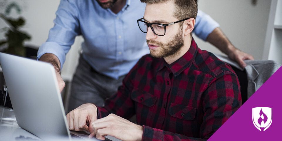 man working on laptop with senior designer giving direction