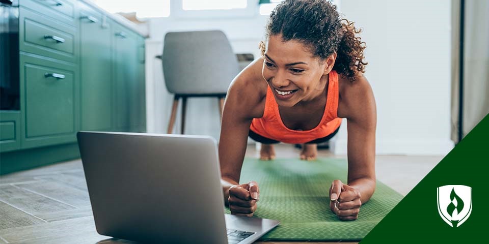 photo of a patient doing a plank at home while watching a laptop reprsenting injury prevention exercises