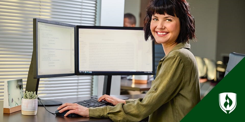 photo of a computer science student sitting at a desk with two monitors