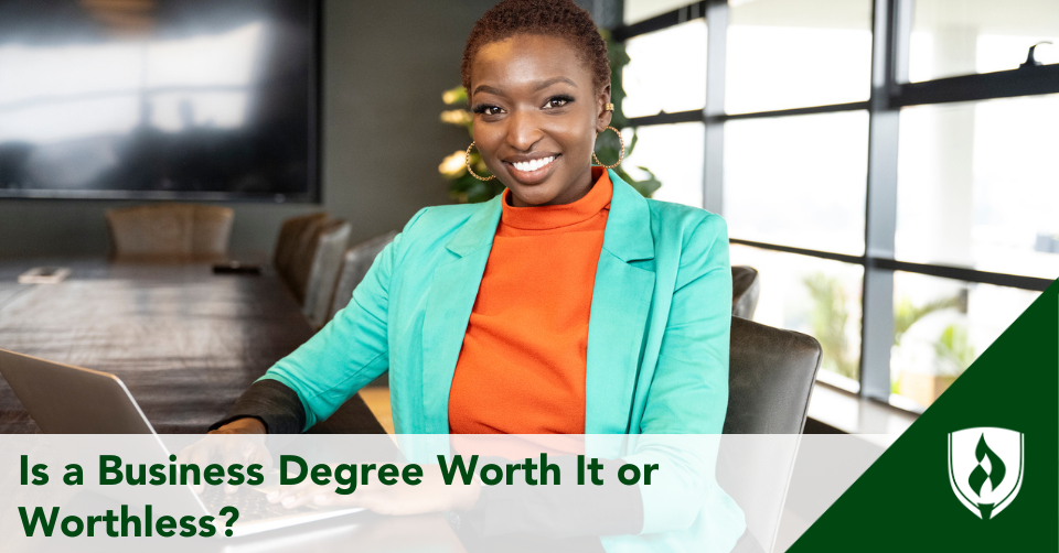 A business student in a turquoise blazer sits in a conference room