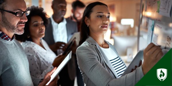 An HR specialist walks new hires through a process using a whiteboard