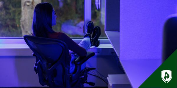 A business professional sits at a desk in purple light