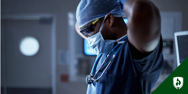 A surgical technologist ties his face mask on