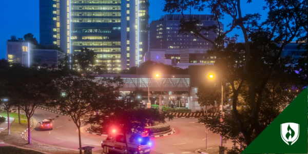 An ambulance races out of a hospital complex at night