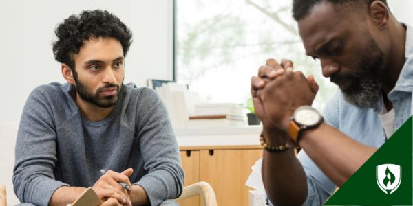A social services assistant sits with a man talking about his trauma