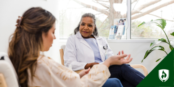 A nurse practitioner with a kind face listens to a patient