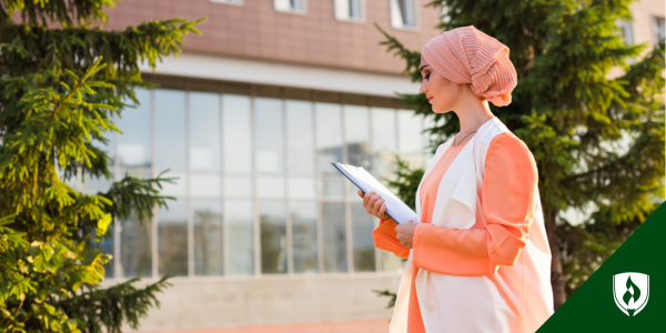 nursing student looking at papers in her hand outside a school building