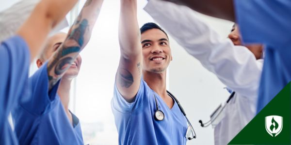 A male nurse adds his hand to a healthcare team group huddle