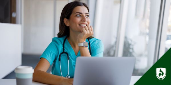 A nurse smiles while sitting at a computer