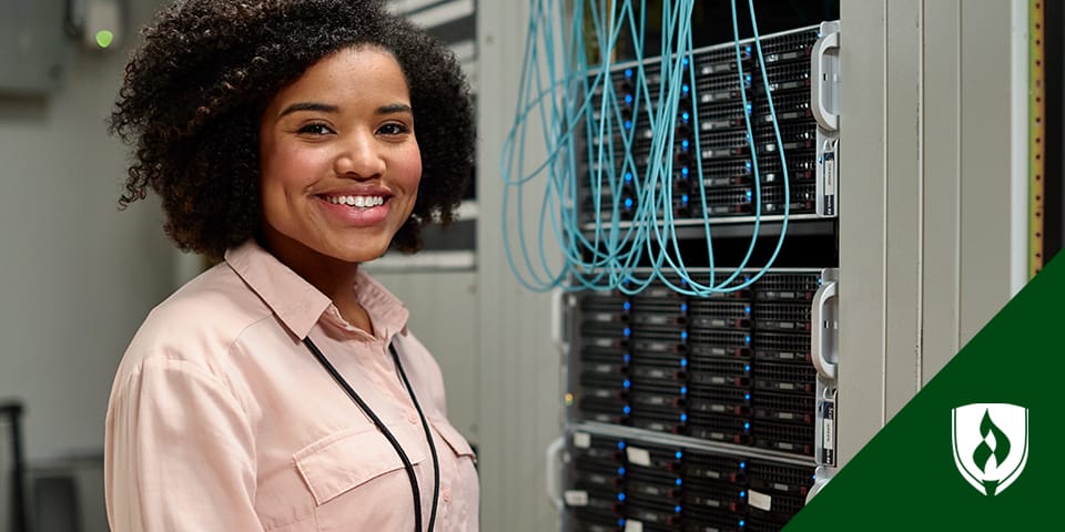 A female network administrator standing in front of a server cluster