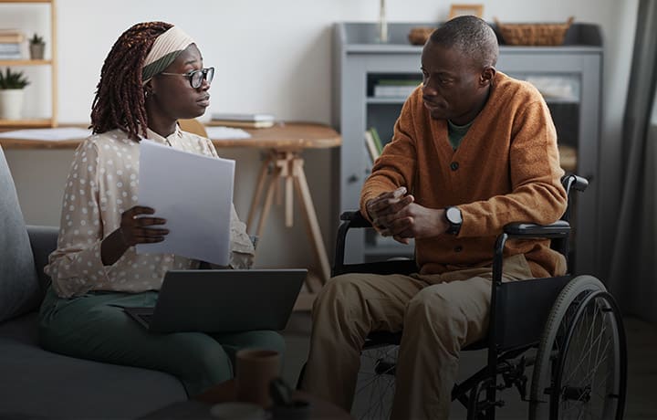 Woman with laptop and papers sitting across from man in wheelchair