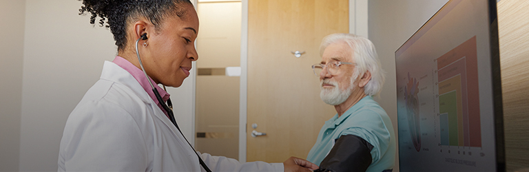 Female nurse practitioner taking blood pressure of grey haired man with glasses