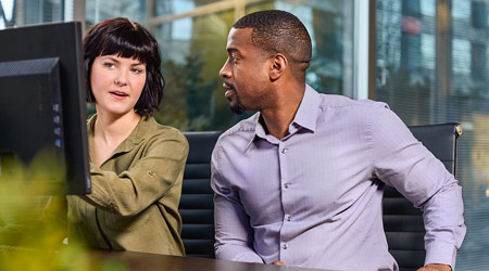 female discussing information on a monitor with a male co-worker